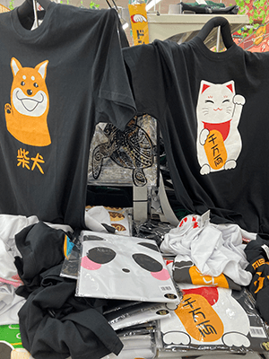 「千万両」と漢字で書かれた小判と思われるものを抱えた猫のTシャツと「柴犬」と漢字で書かれた犬のTシャツ