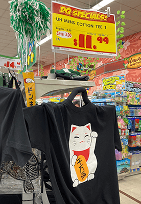 「千万両」と漢字で書かれた小判と思われるものを抱えた猫のTシャツと英語表記の値札
